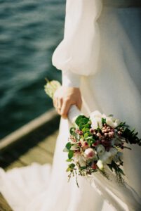 Eine Frau in weißem Brautkleid mit einem Brautstrauß in der Hand